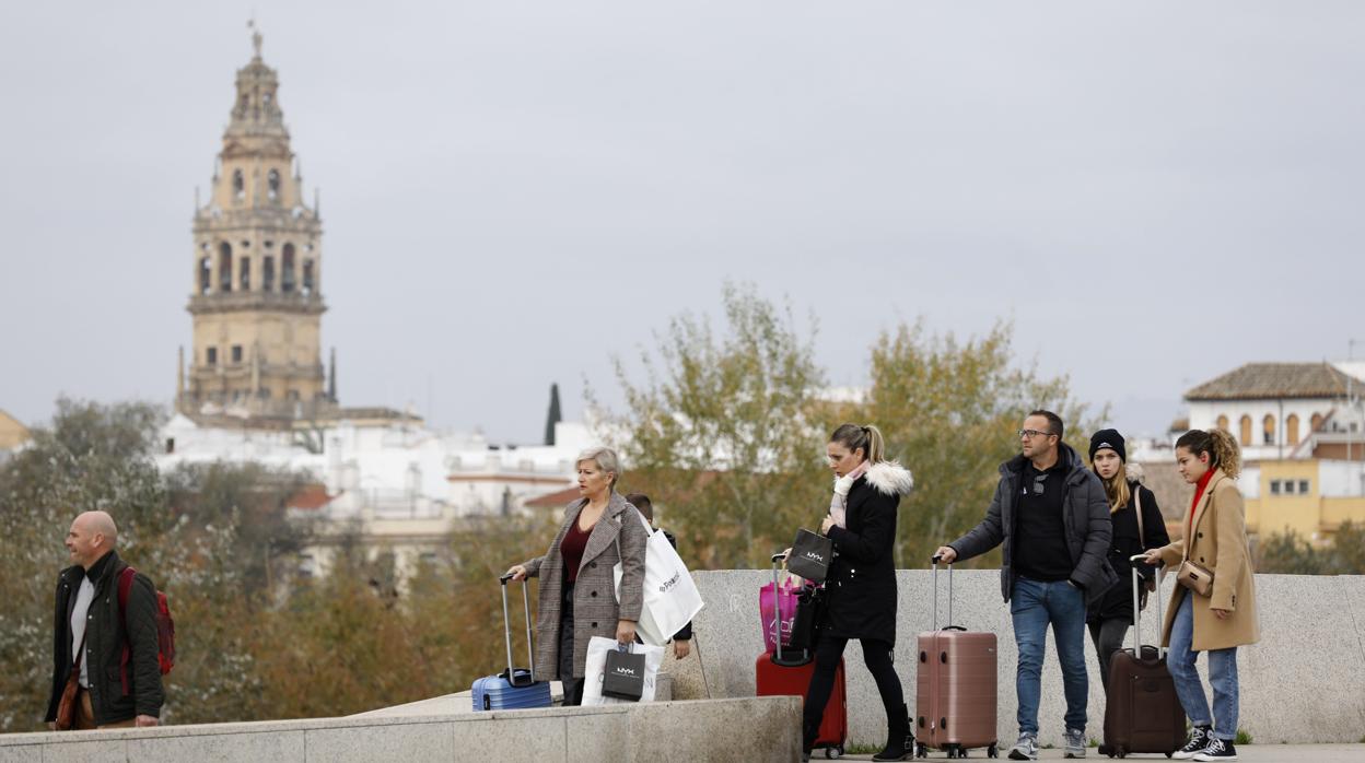Turistas con maletas en el Puente de Miraflores, con la torre de la Mezquita-Catedral de fondo