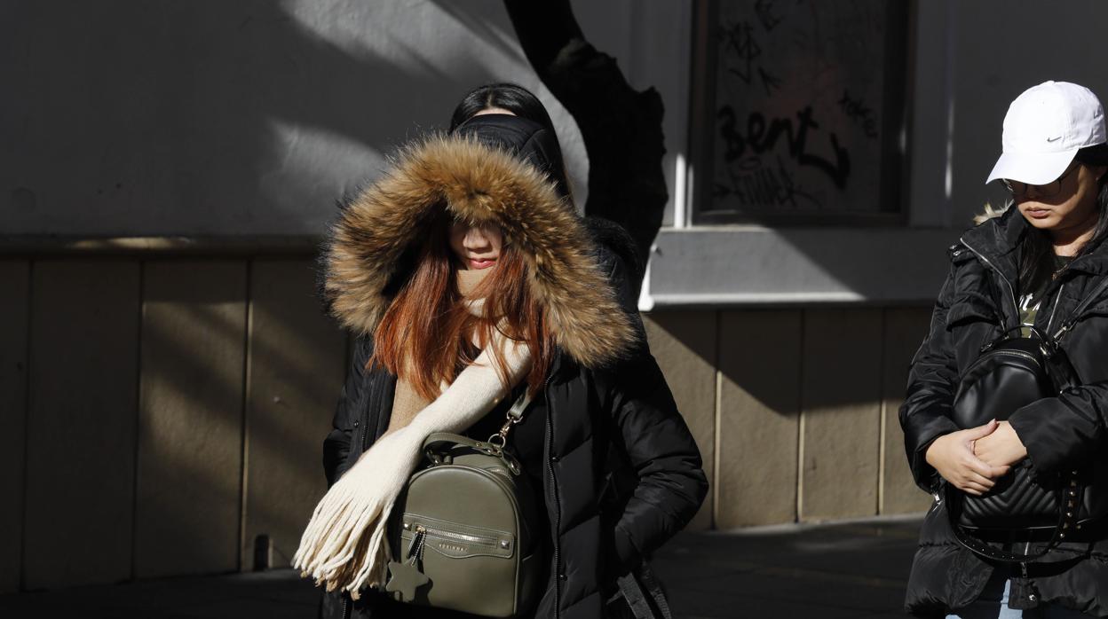 Una chica pasea bajo el sol pero bien abrigada por la capital