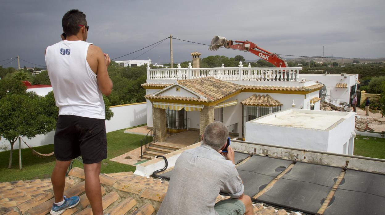 Unos vecinos contemplan el derribo de una vivienda ilegal en El Palmar