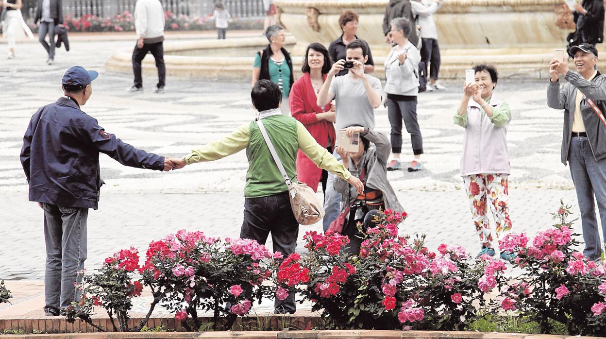 Turistas chinos en la plaza de España de Sevilla se toman fotos de recuerdo