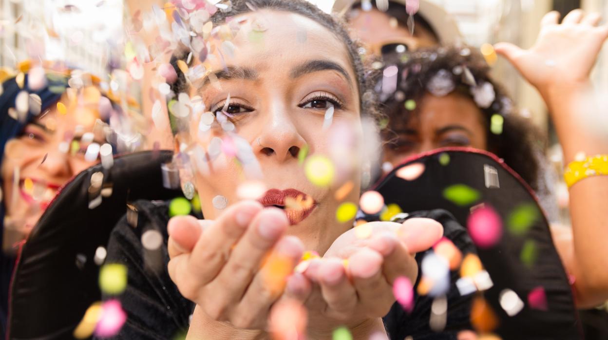 Una mujer sopla papelillos en las calles de Cádiz durante el carnaval