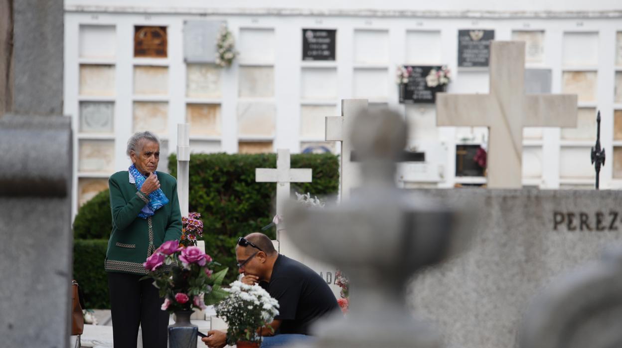 Dos personas en el cementerio de San Rafael de Córdoba colocan flores