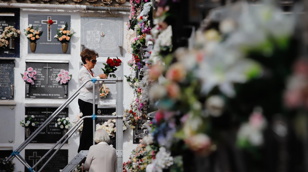 Dos mujeres ponen flores en un cementerio