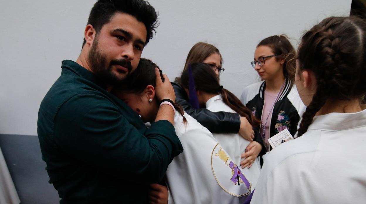 Un hombre consuela a una nazarena de Pasión tras suspender su estación de penitencia el Miércoles Santo de 2019