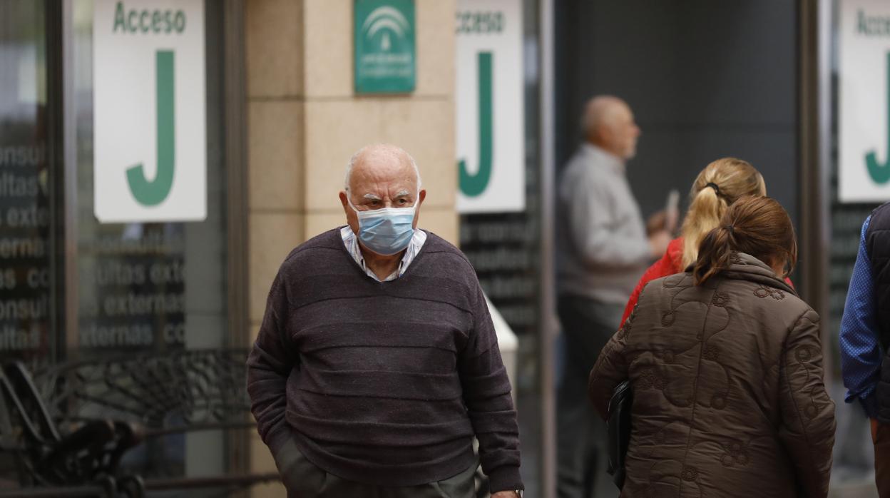 Una persona mayor con mascarilla saliendo de un hosptial