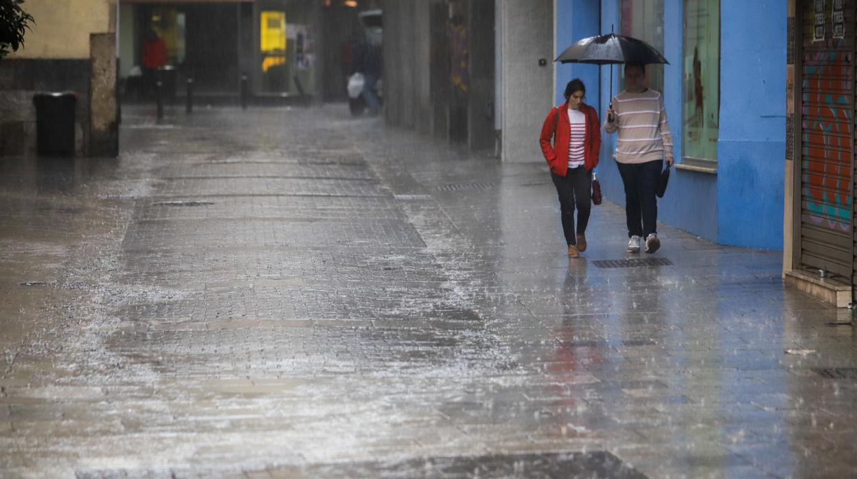 Dos jóvenes se cubren la lluvia en las calles del centro de Córdoba