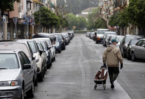 Un hombre pasea con un carro de la compra por un barrio de Córdoba