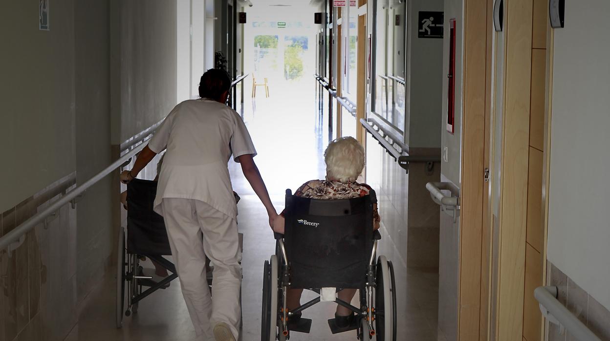 Una profesional atiende a dos residentes en un centro de mayores