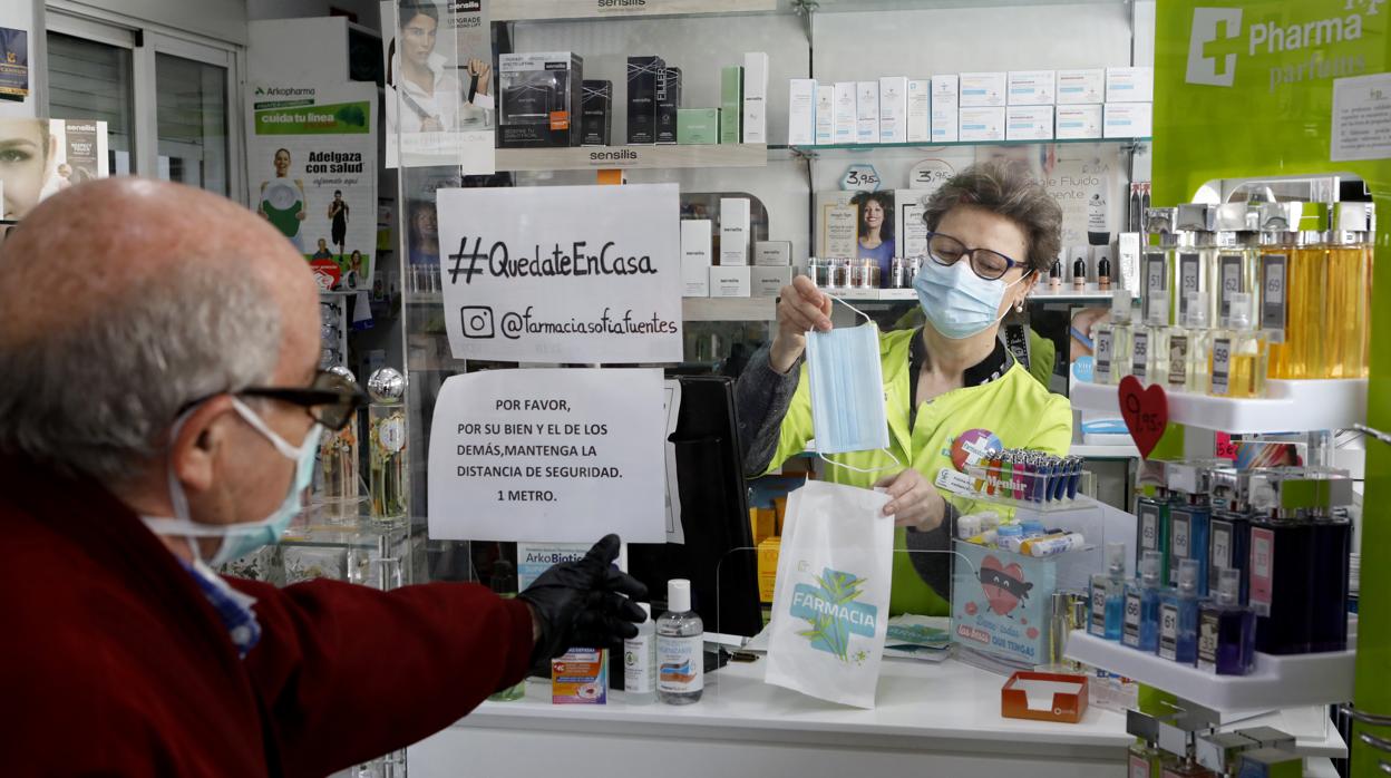 Un hombre compra una mascarilla en una farmacia de Córdoba