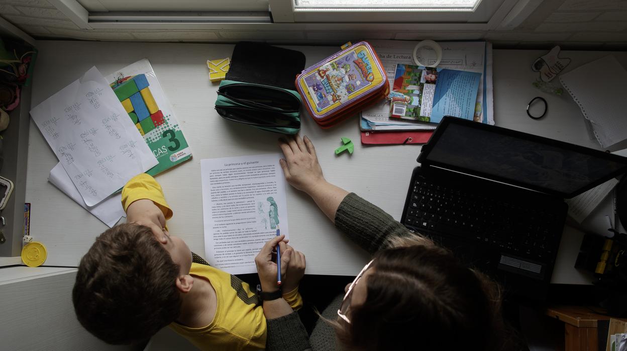 Un alumno estudia en su casa junto a su madre