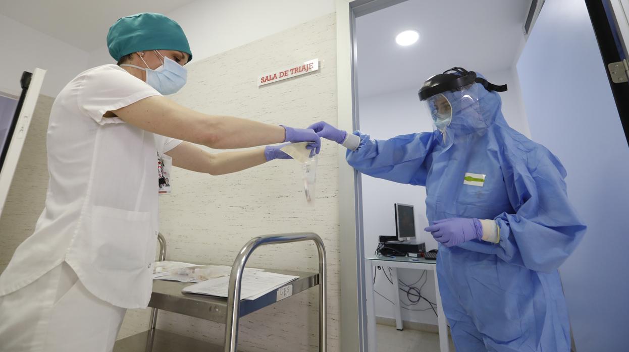 Una profesional sanitaria entrega a otra las muestras de un test en el hospital de la Cruz Roja de Córdoba