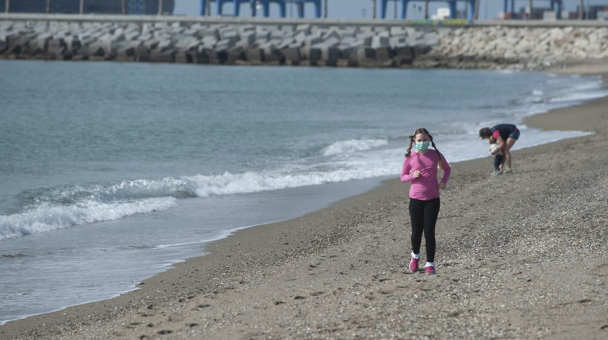 Una niña recorre la playa de la Malagueta con su correspondiente mascarilla