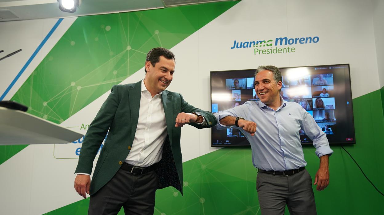 Juanma Moreno y Elías Bendodo se saludan con el codo al comenzar el acto virtual de su partido