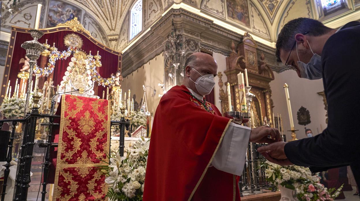 Un miembro de la Matriz recibe la Comunión de manos del párroco de la Asunción