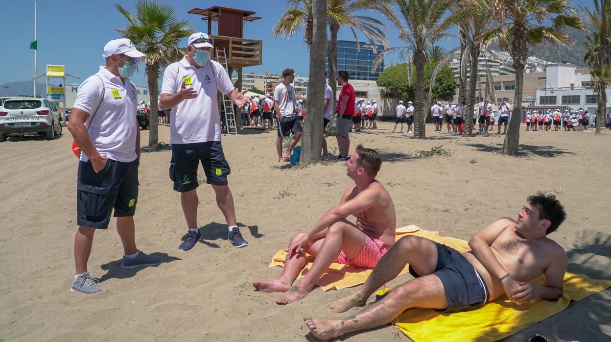 Un par de vigilantes de la playa conversa con dos usuarios de la playa de Marbella