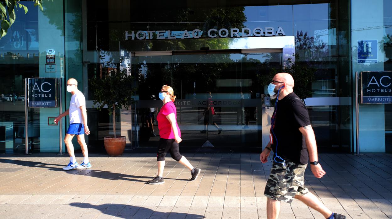 Varias personas pasean delante de la puerta de un establecimiento hotelero de Córdoba