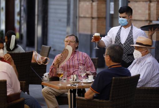 Un hombre combate el calor con un abanico en una terraza de la capital