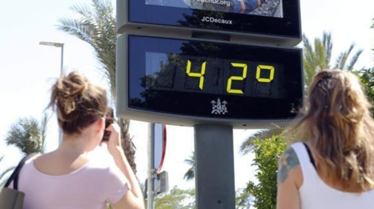 Dos mujeres observan un termómetro que marca 42 grados