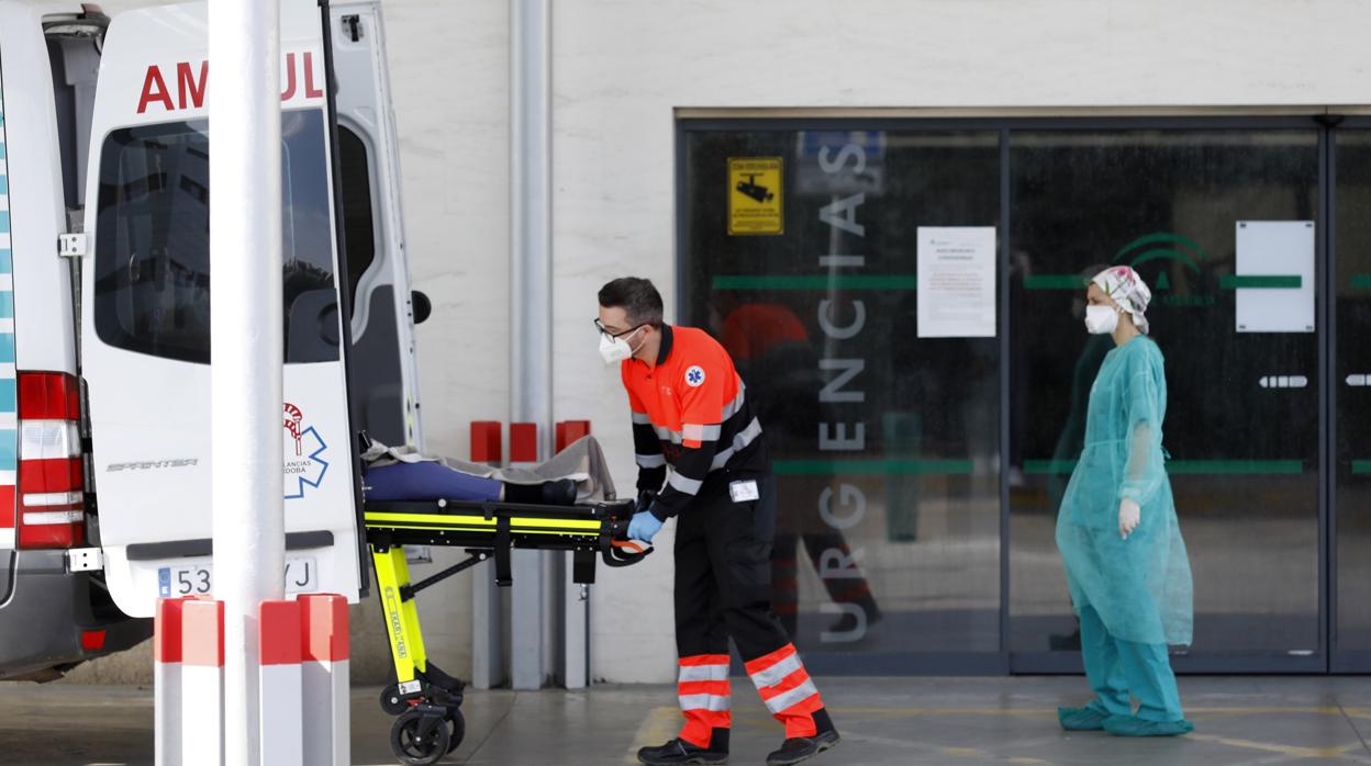 Dos sanitarios en la puerta de Urgencias del Hospital Reina Sofía de Córdoba con un enfermo