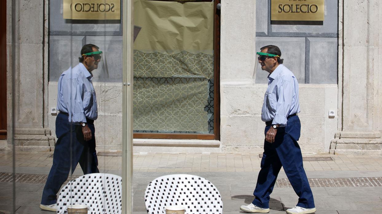 Un hombre pasea con una pantalla protectora por las calles de Málaga, una de las provincias con más hospitalizados junto a Granada