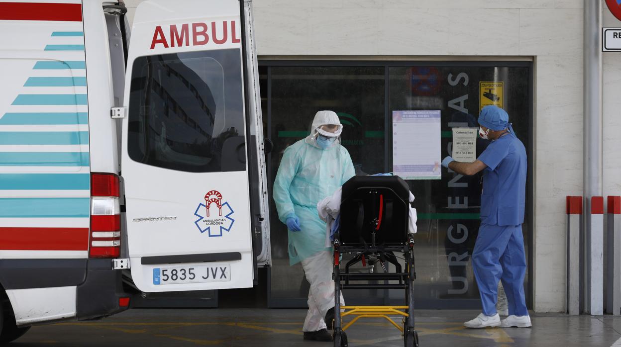 Dos sanitarios atienden a un paciente en la puerta de Uregencia del Reina Sofía