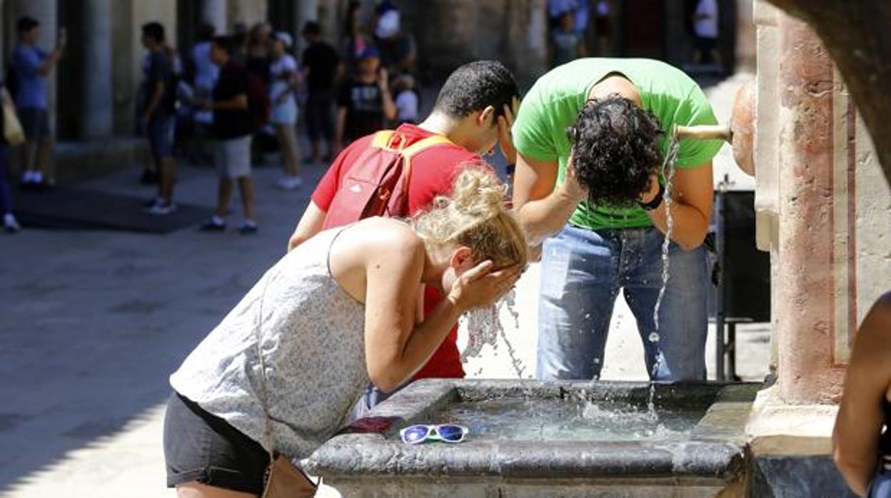 Unos turistas se refrescan en una fuente de Córdoba