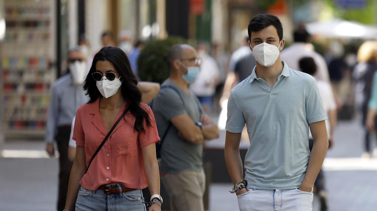 Dos jóvenes, con mascarilla por una calle de Córdoba