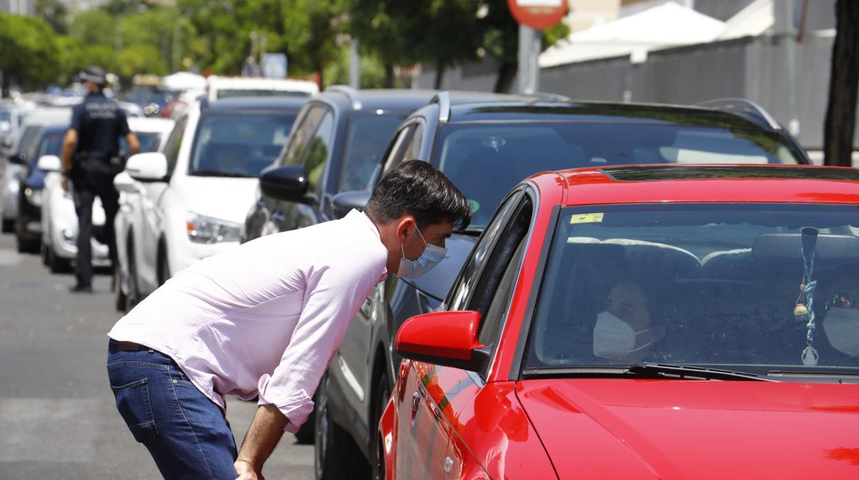 Un joven conversa con una chica en la cola de coches del centro de salud Castilla del Pino