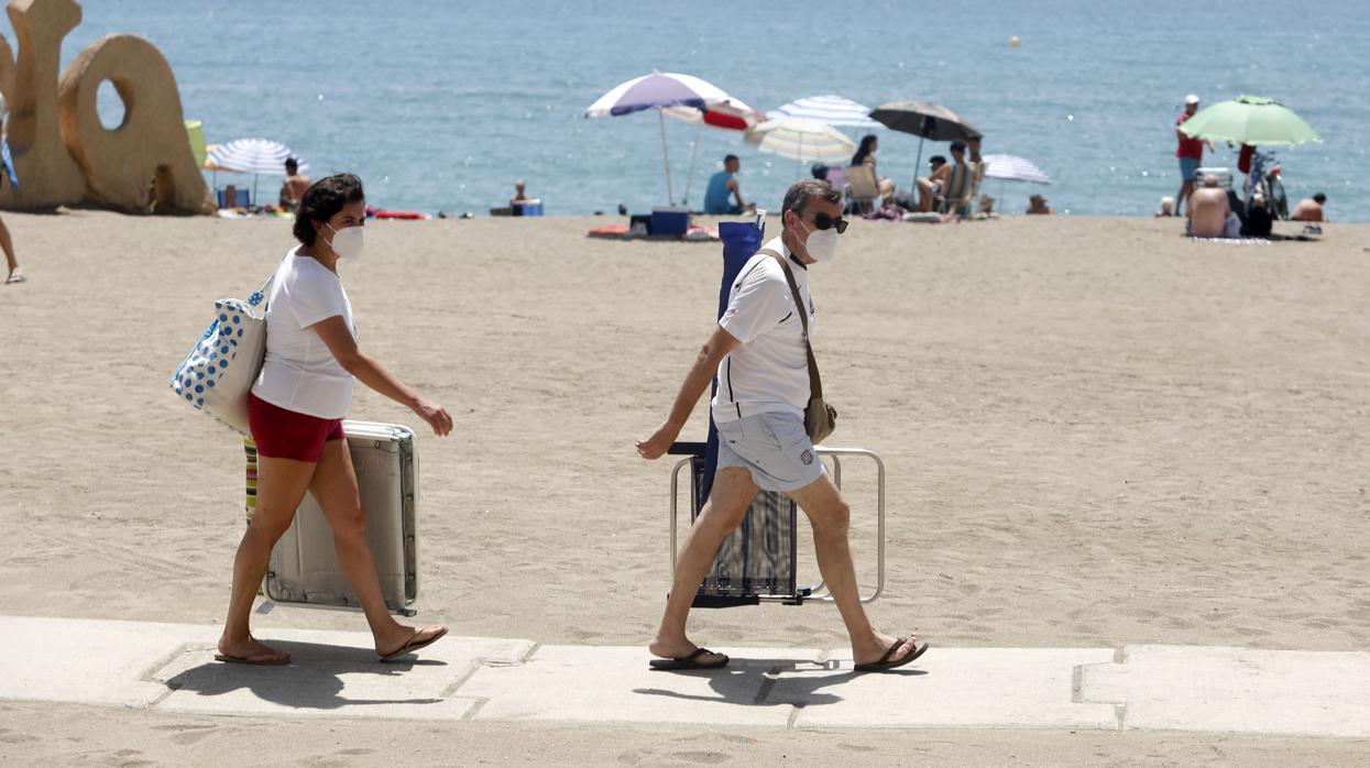 Dos personas con mascarilla acceden a la playa de La Malagueta