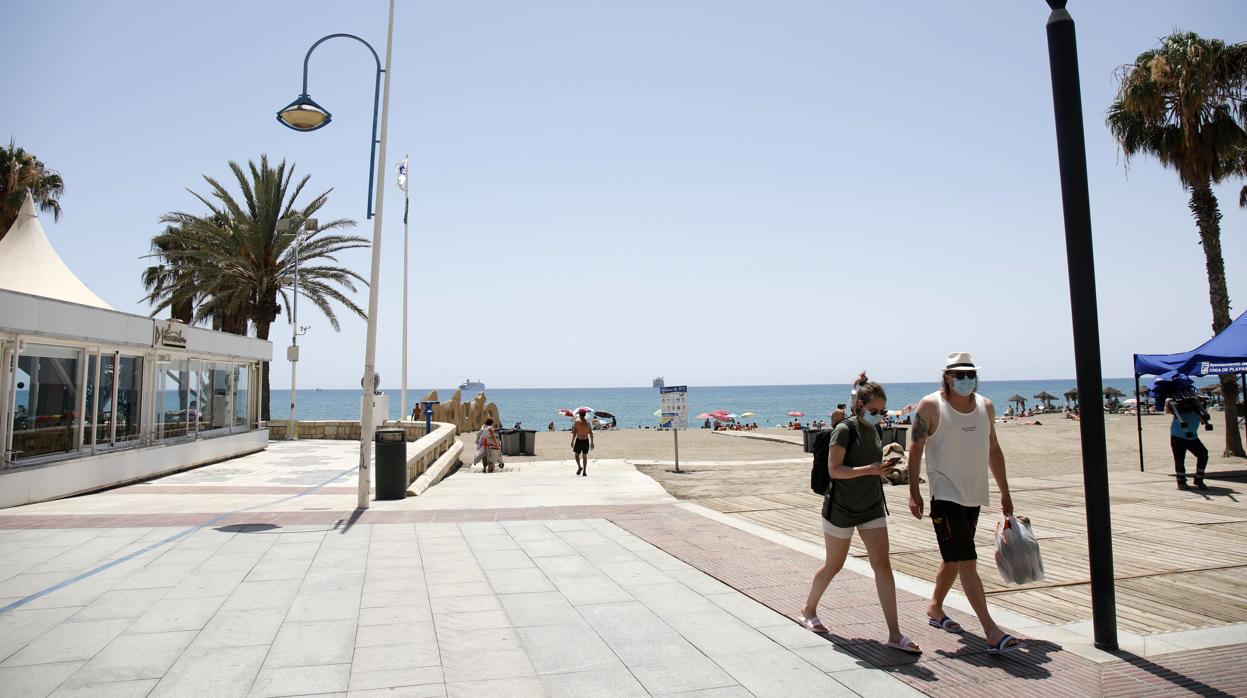 Dos personas con mascarilla puesta en la Playa de la Malagueta