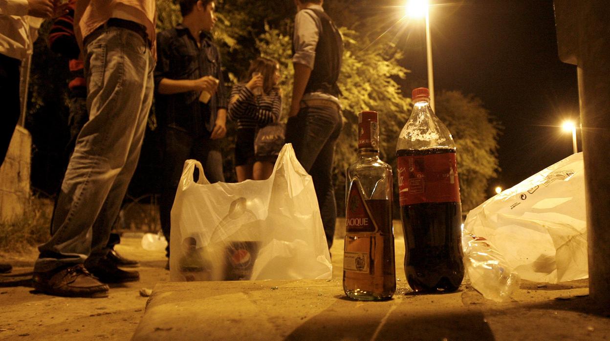 Un grupo de jóvenes junto a una botella de refresco y otra de alcohol