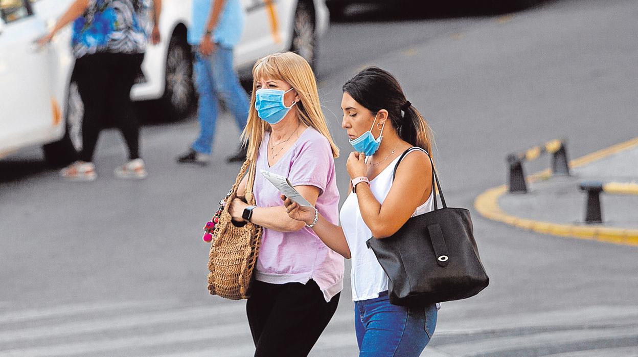 Dos mujeres con mascarilla pasean por delante del hospital Virgen del Rocío de Sevilla