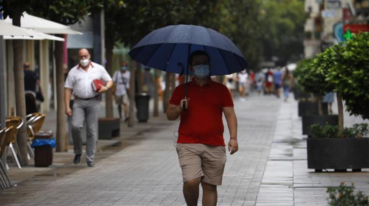 Unhombre camina por el Centro de Córdoba con un paraguas en la mañana del lunes