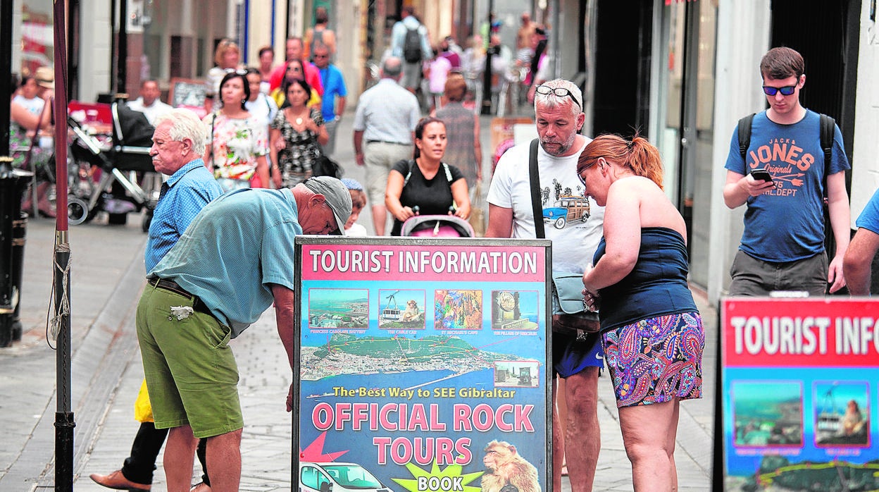 Varios turistas observan un cartel escrito en inglés en una calle de Gibraltar