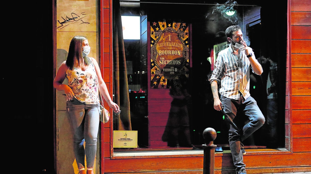 Dos jóvenes fuman separados a las puertas del Bourbon en la noche del viernes