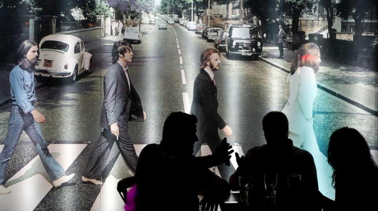 Clientes del Long Rock conversan frente al panel de los Beatles en «Abbey Road» en la noche del viernes