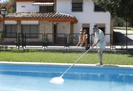 Un hombre limpia su piscina en Trassierra