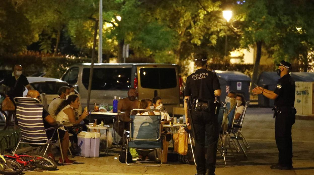 Dos agentes de la Policía Local hablan con un grupo de personas