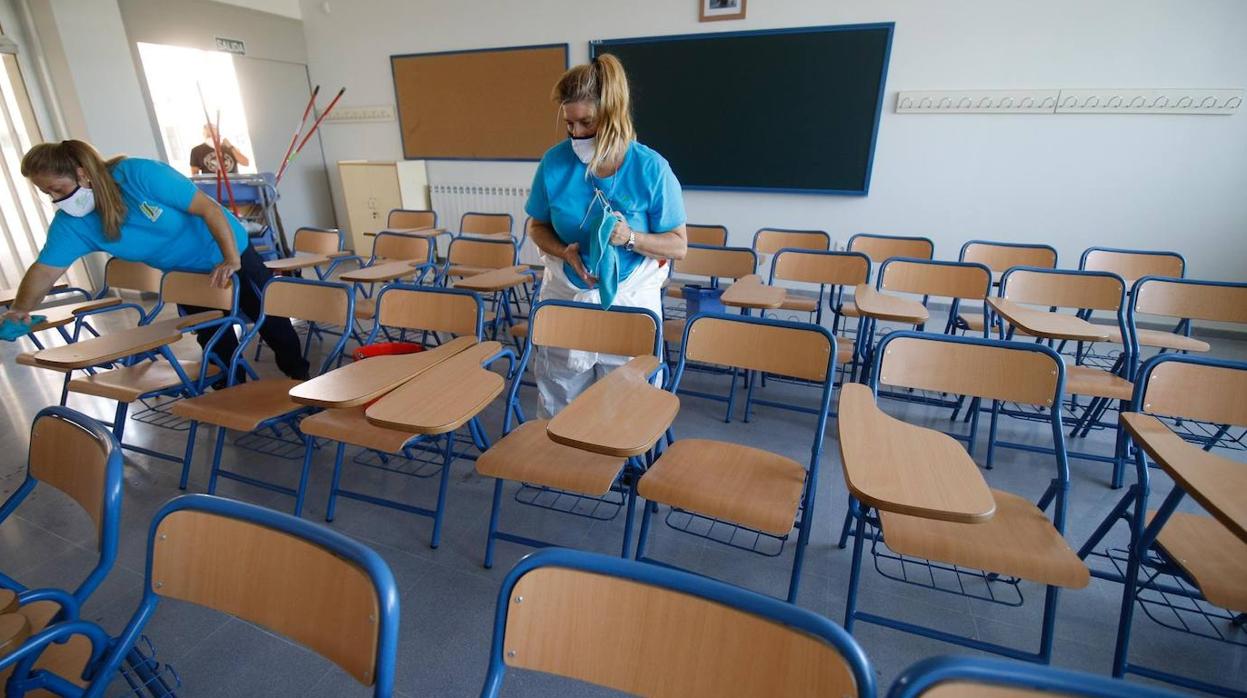 Dos trabajadoras de Sadeco limpian una clase de un colegio