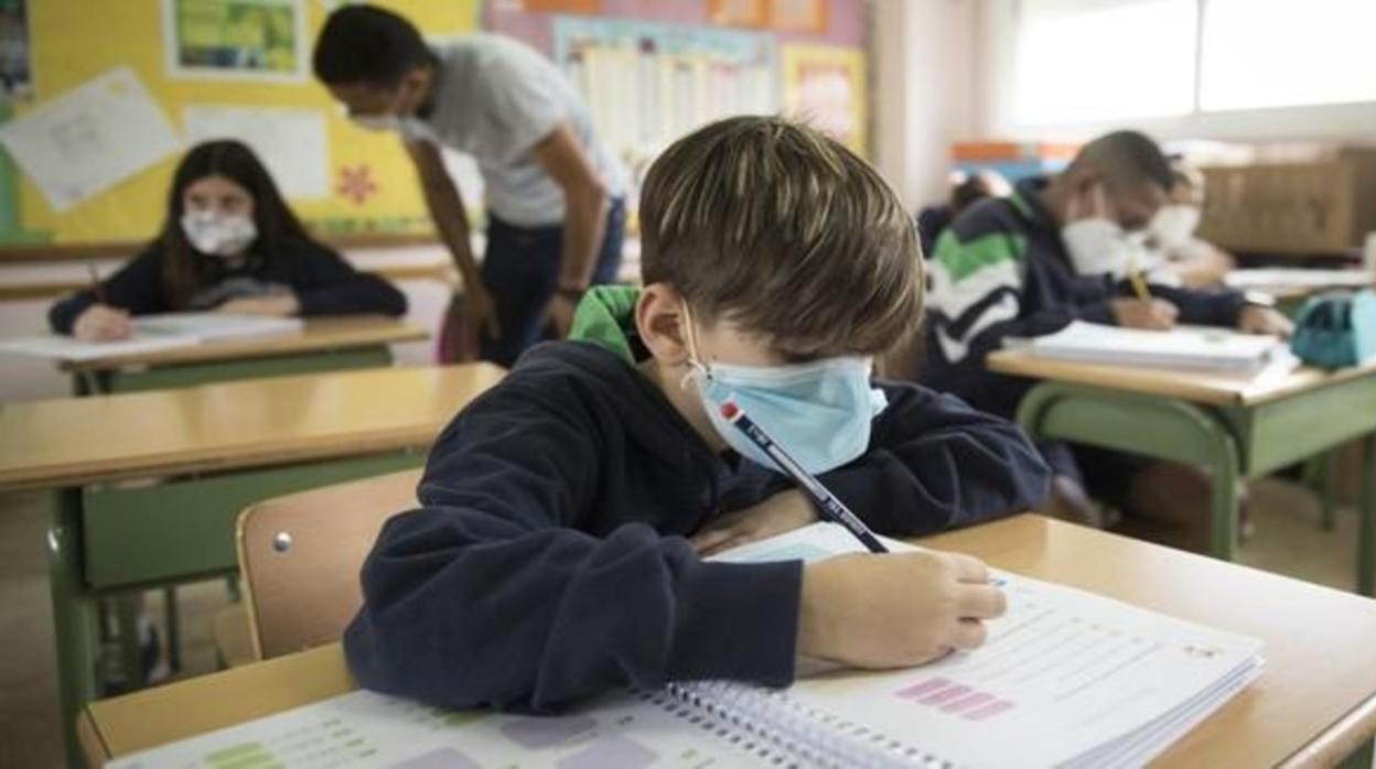 Niño haciendo deberes en clase con mascarilla