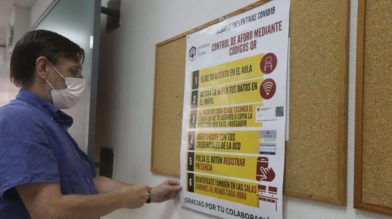 Un trabajador de la UCO coloca un cartel sobre los códigos QR