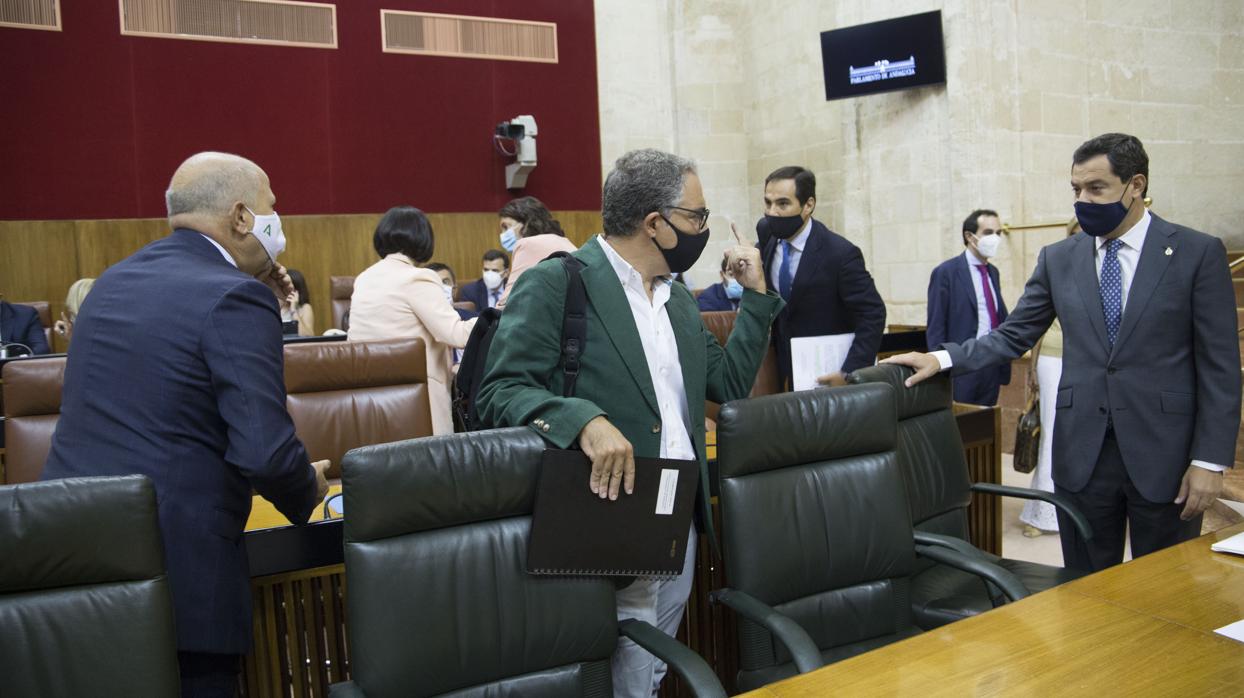 El presidente andaluz, Juanma Moreno, dialoga con Elías Bendodo antes de ocupar sus bancos verdes en el Parlamento de Andalucía