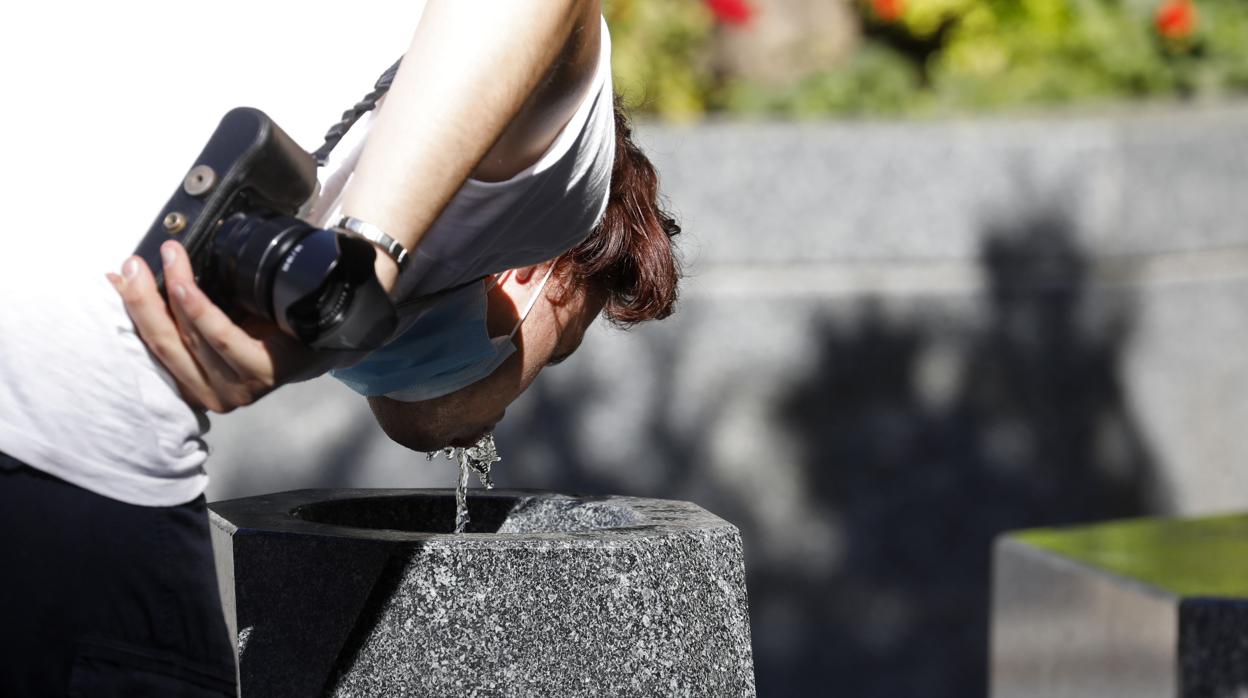 Un joven se refresca bebiendo agua de una fuente en Córdoba