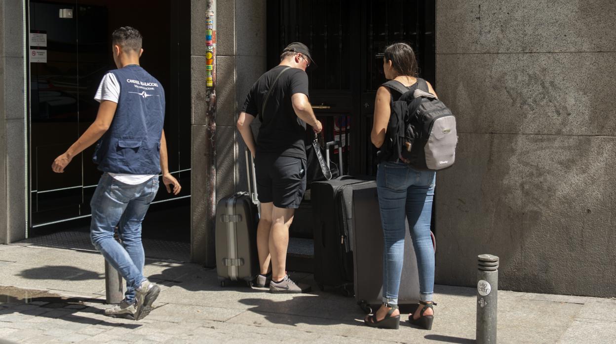 Una pareja entra a un bloque con pisos turísticos