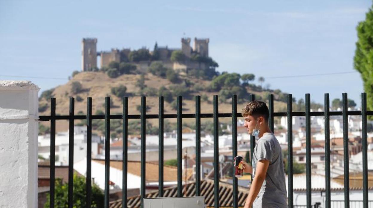 Un joven camina por Almodóvar con una bebida energética y el castillo al fondo