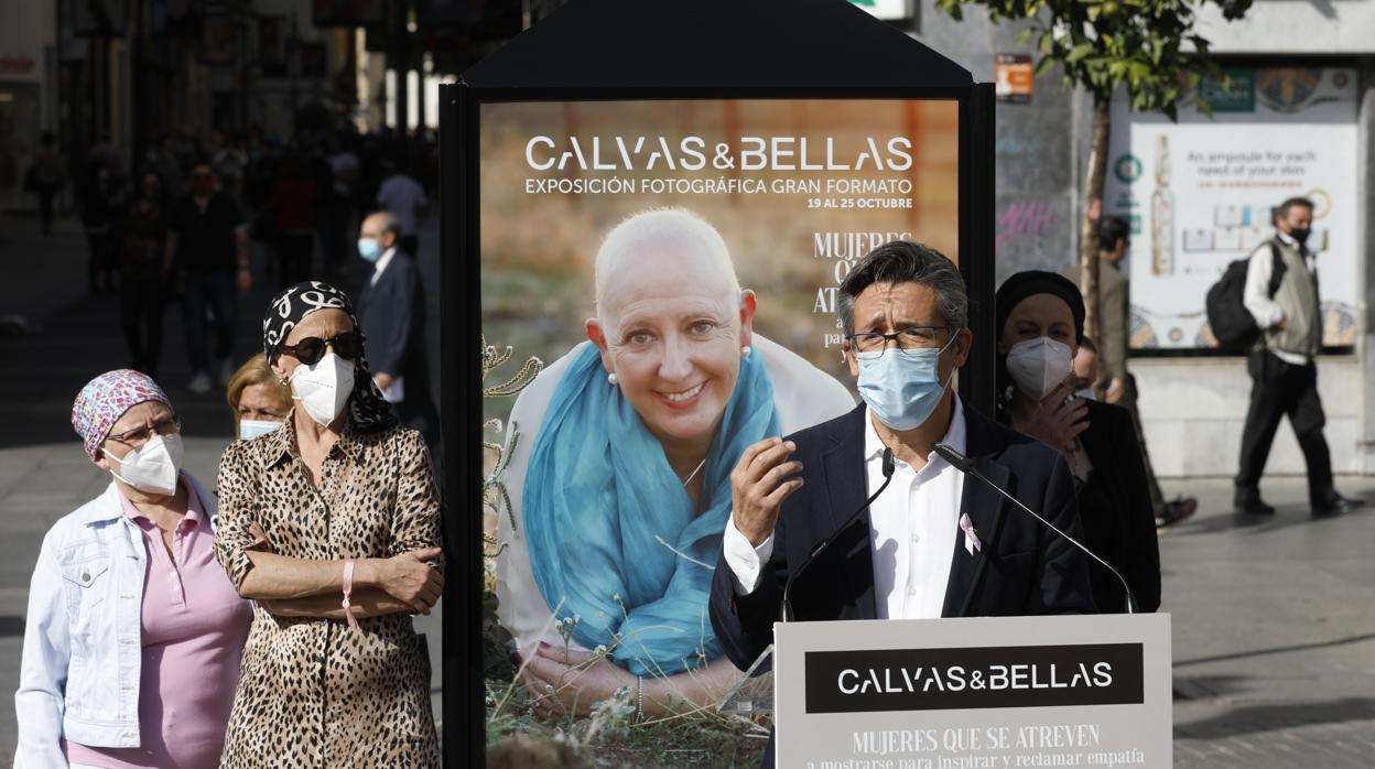 Caridad, a la derecha del cartel con un pañuelo oscuro mientras habla el doctor De la Haba