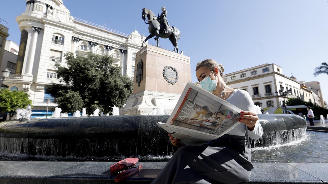 Una joven lee el periódico ABC Córdoba en la plaza de Las Tendillas