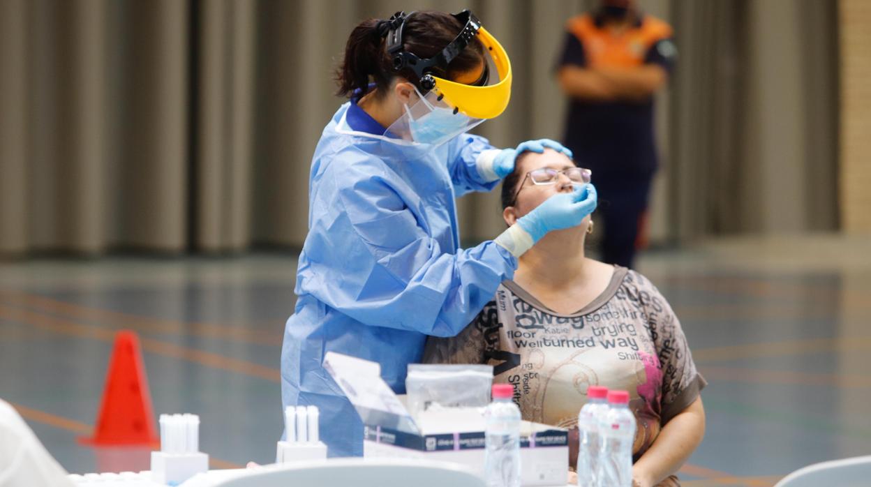 Un sanitario toma muestras de una mujer para hacerle una prueba diagnóstica de coronavirus