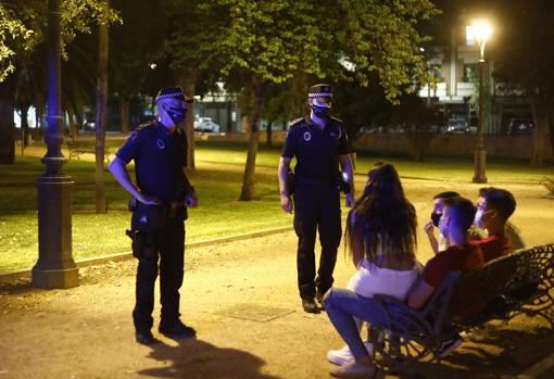 Dos policías locales de Córdoba junto a un grupo de jóvenes en un banco