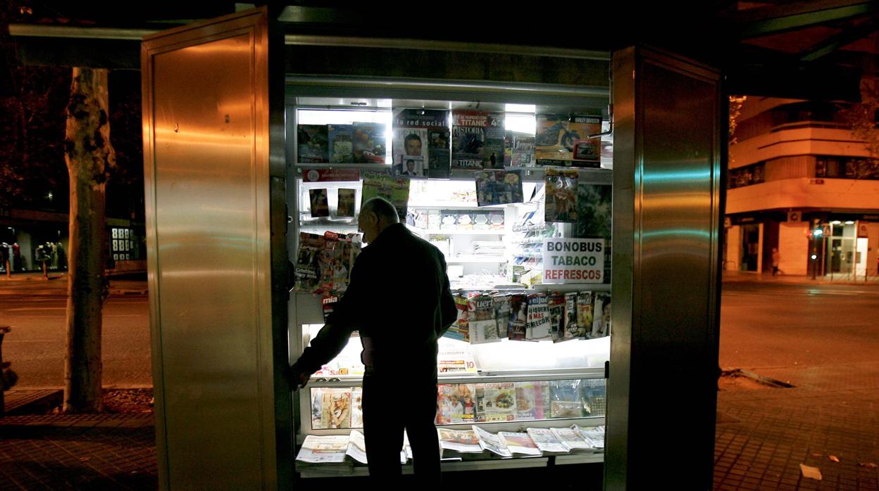 Un quiosquero abriendo aún sin la luz del día